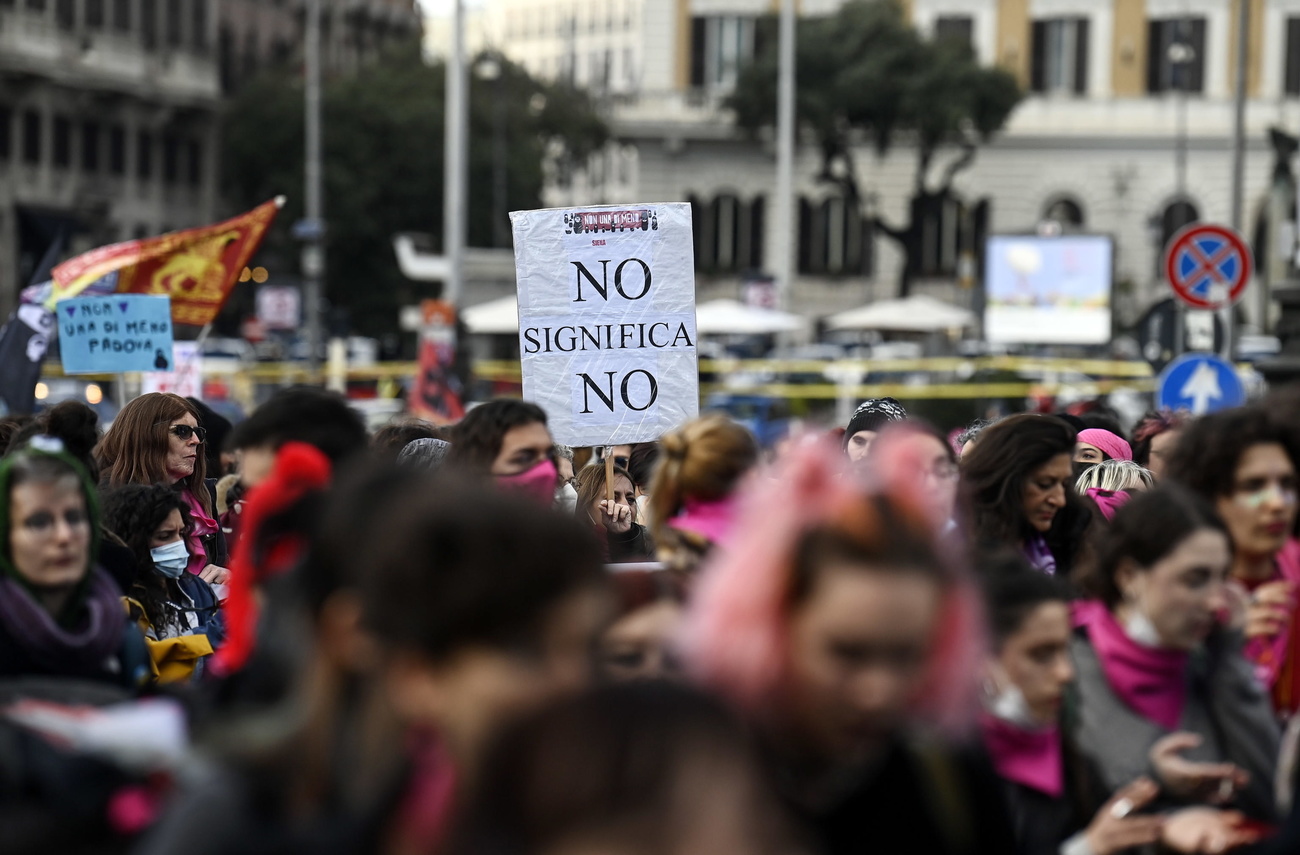 cartello si staglia da folla di persone con scritta NO SIGNIFICA NO