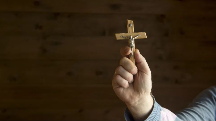 a cross with jesus is held up. there is a satanic panic in the bern mountains