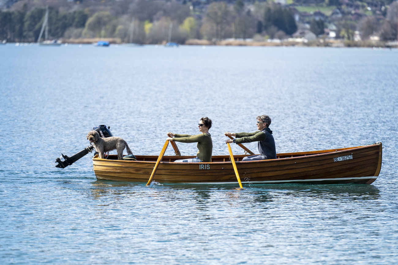 Deux personnes et un chien dans une barque sur un lac