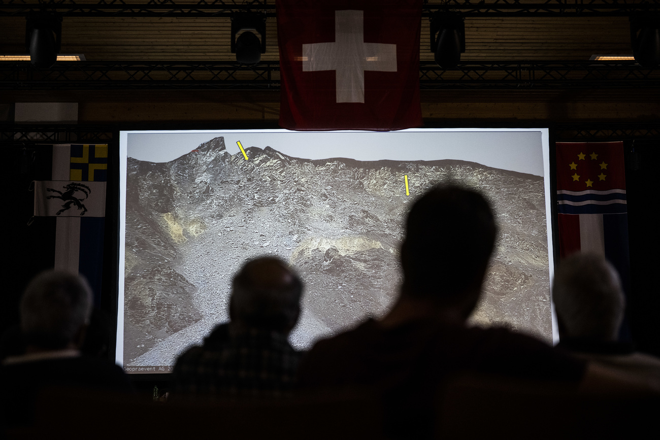 Gente viendo una presentación sobre el posible derrumbe de la montaña Brienz/Brinzauls.