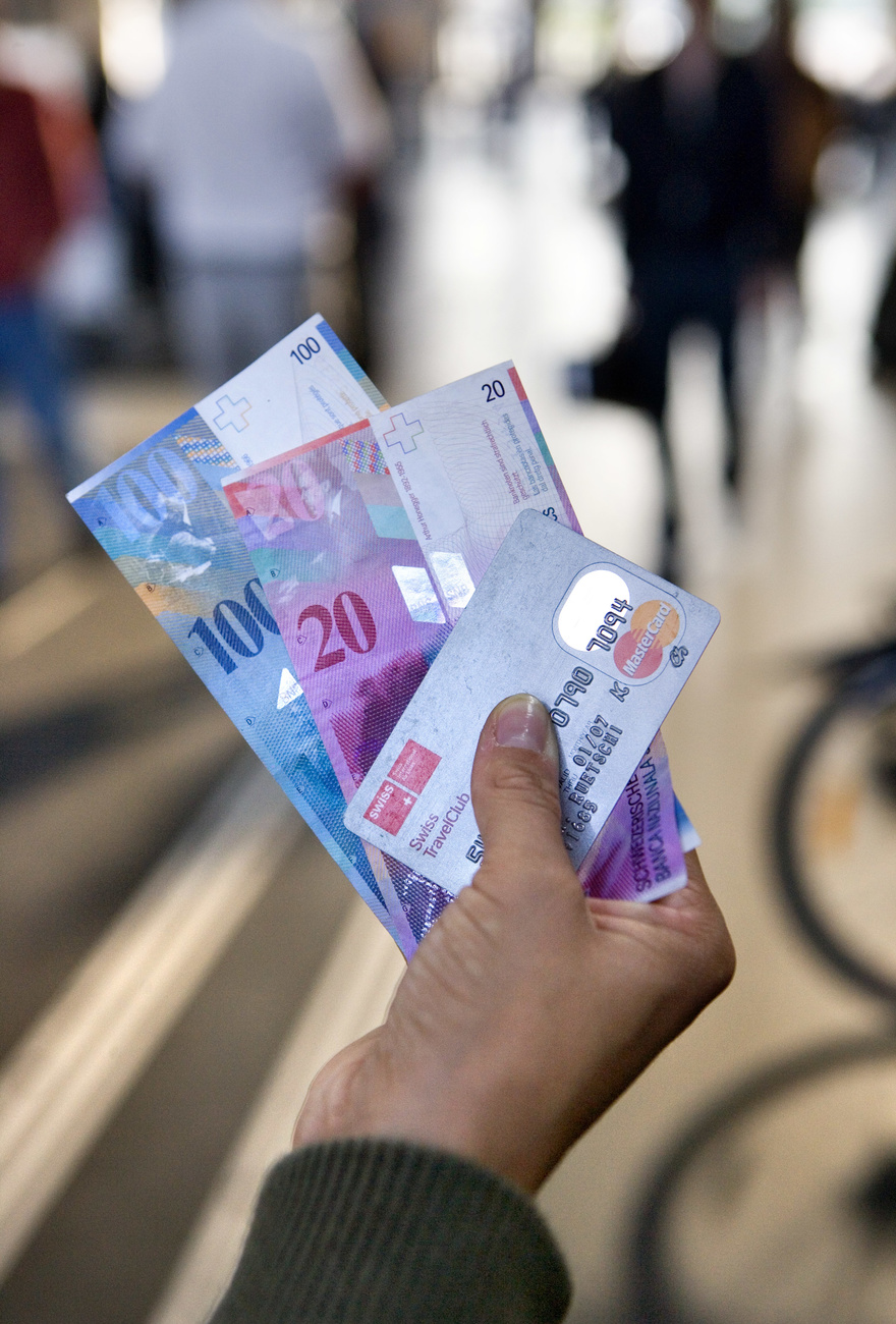 mano tiene banconota da 100 franchi, banconota da 20 franchi e carta di credito