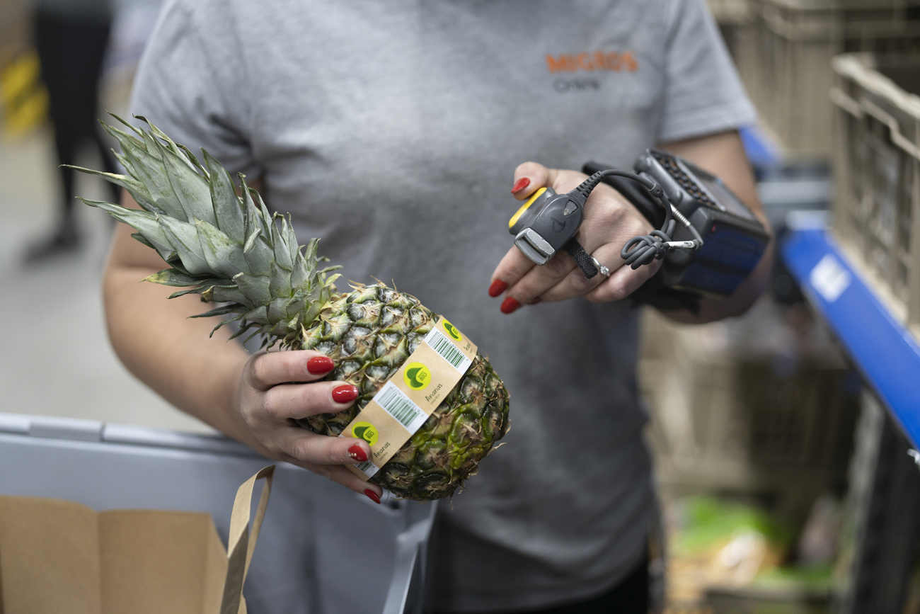 Impiegata di supermercato controlla il prezzo di un ananas.