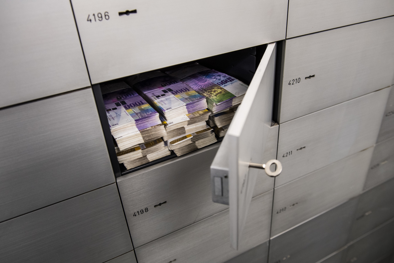 Una cassetta di sicurezza aperta con molte banconote svizzere.
