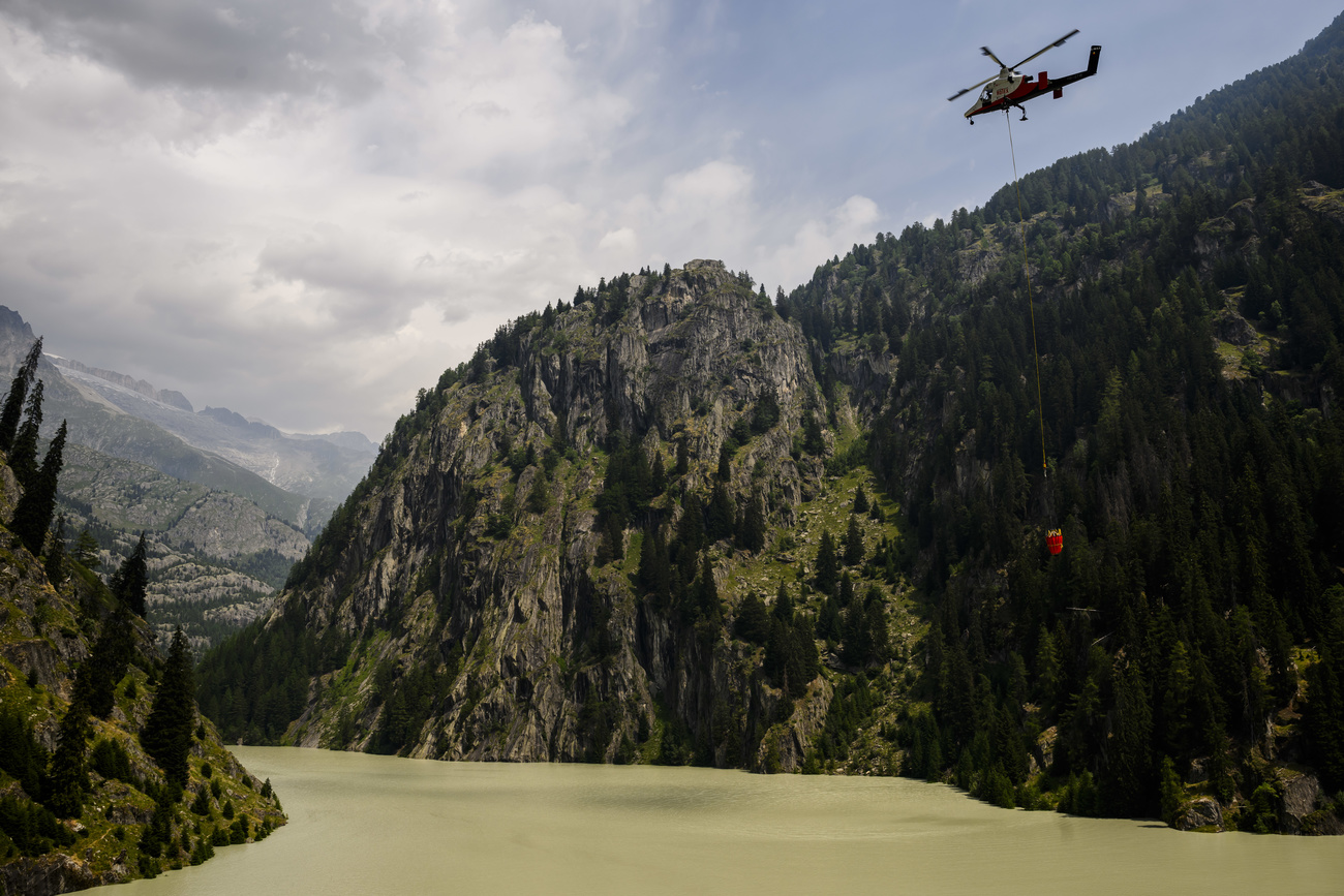 Ein Löschhelikopter nähert sich einem Stausee