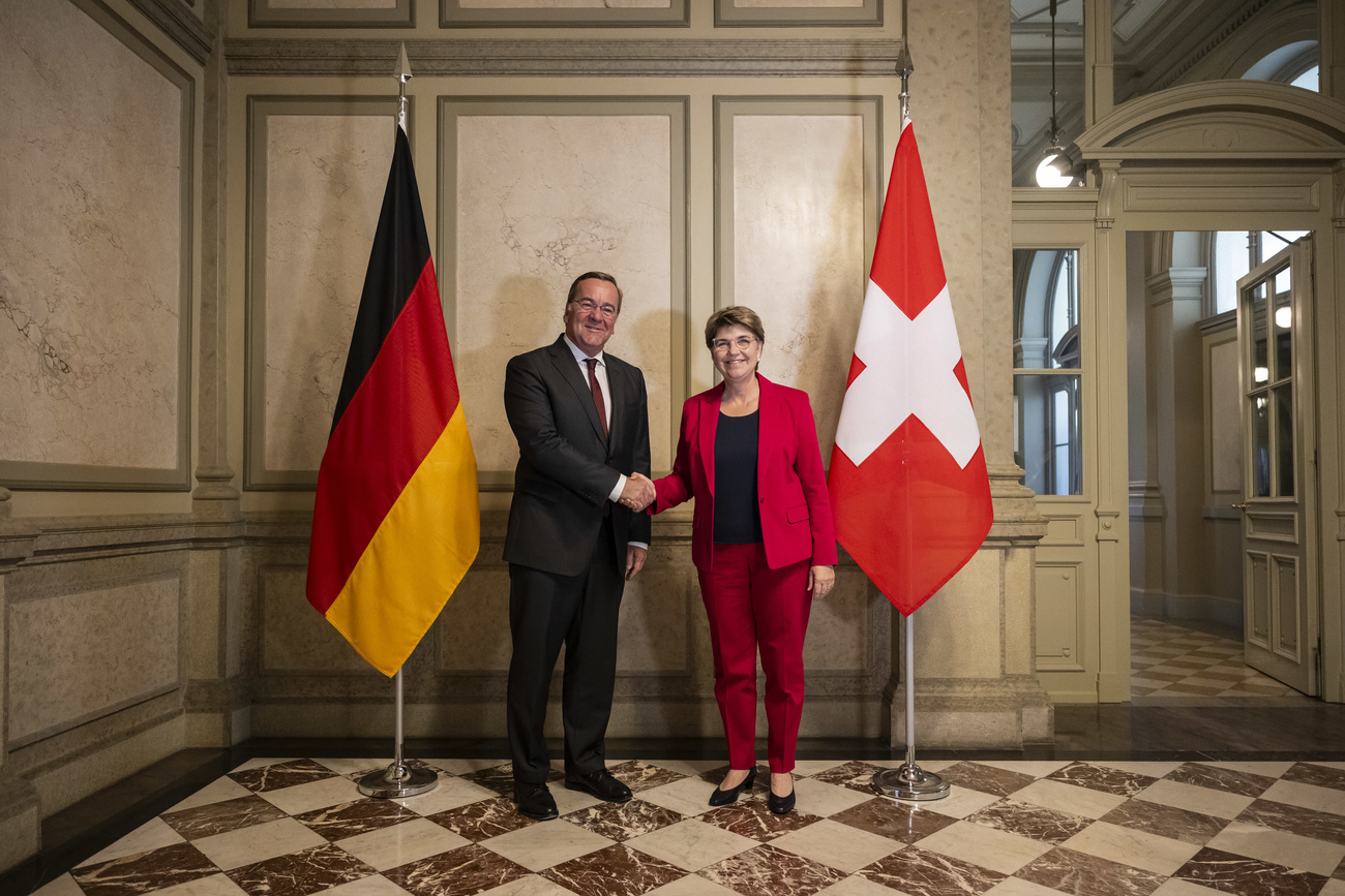 Boris Pistorius and Viola Amherd shaking hands in front of German and Swiss flags