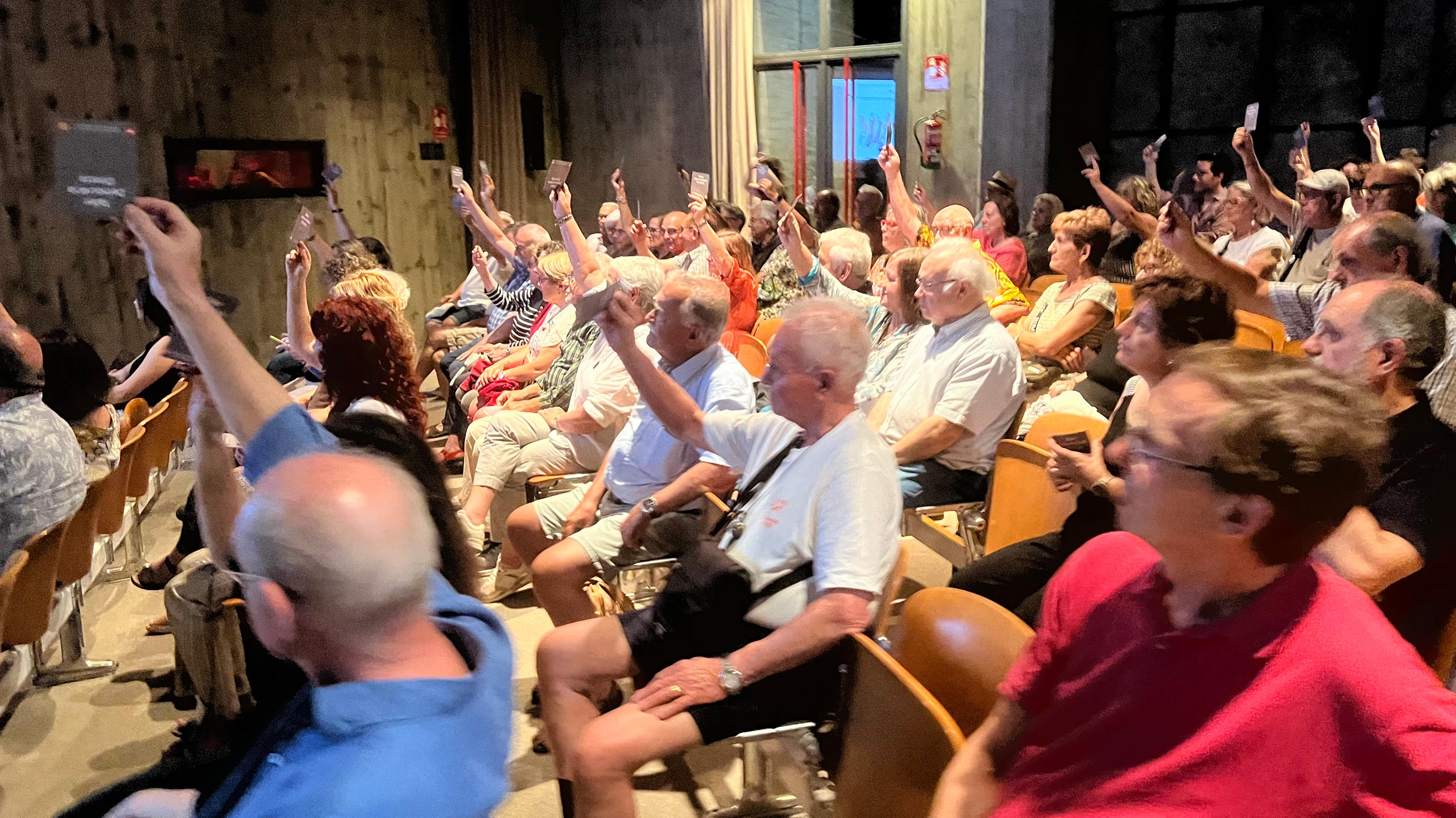 gente con la mano levantada con una tarjeta votando