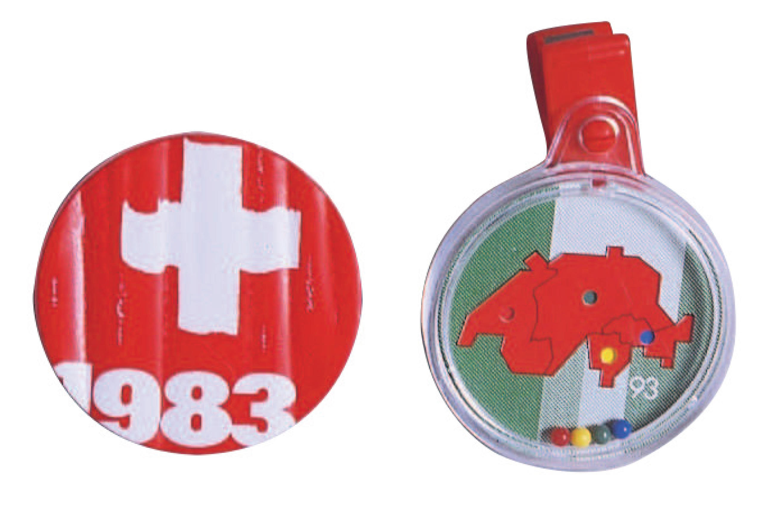 2 badges - one depicting the Swiss Cross and date 1983, the other plastic with the swiss map fill in red