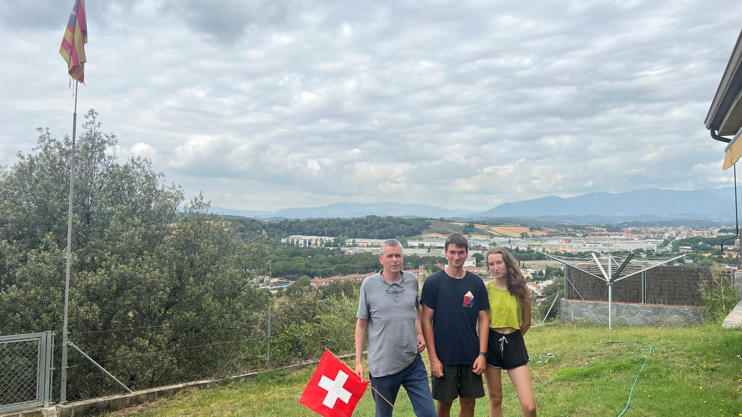 Hombre y sus hijos posando en el jardín de su casa con una bandera suiza