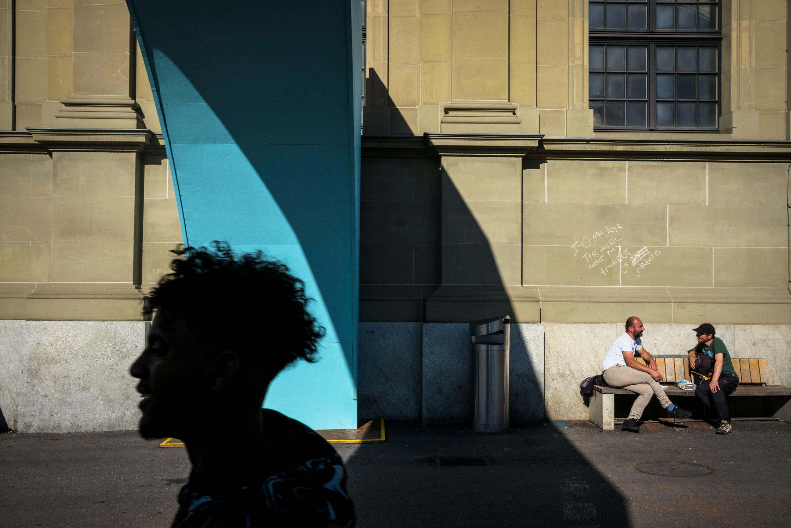 silhouette d un passant et deux hommes sur un banc