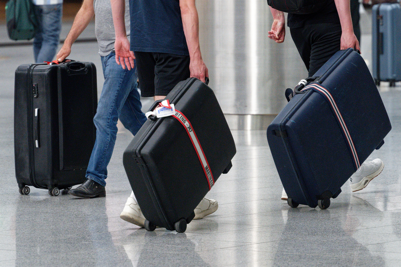 Zwei Menschen ziehen je einen Koffer.