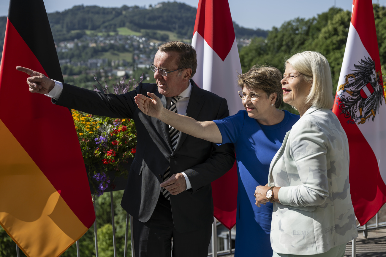 Foto de três ministros em frente às bandeiras da Alemanha, da Suíça e da Áustria