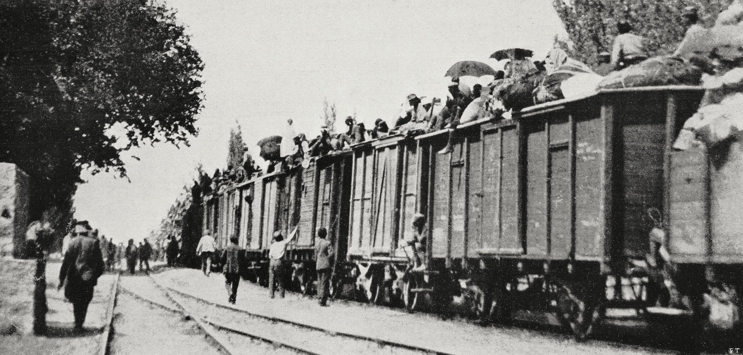 gente ammassata su vagoni ferroviari in una foto in bianco e nero