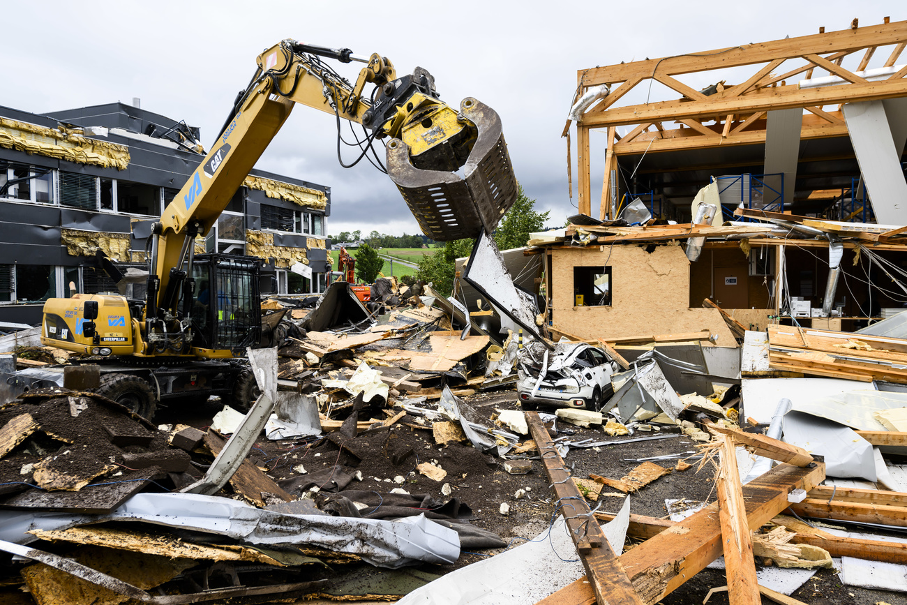 A construction vehicle stands next to a destroyed bulding in La Chaux-de-Fonds