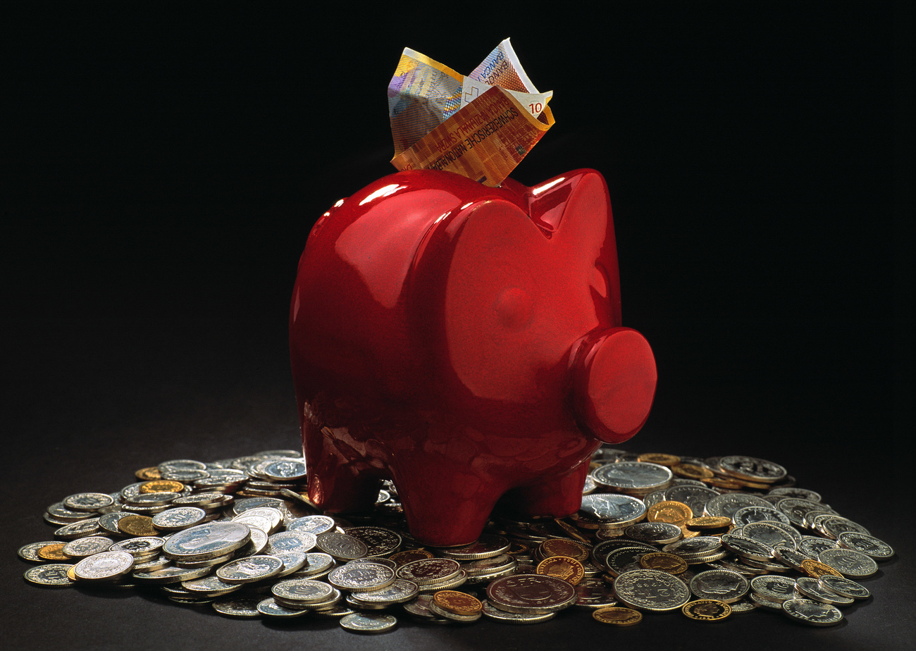 Photo of a red piggy bank with money all around