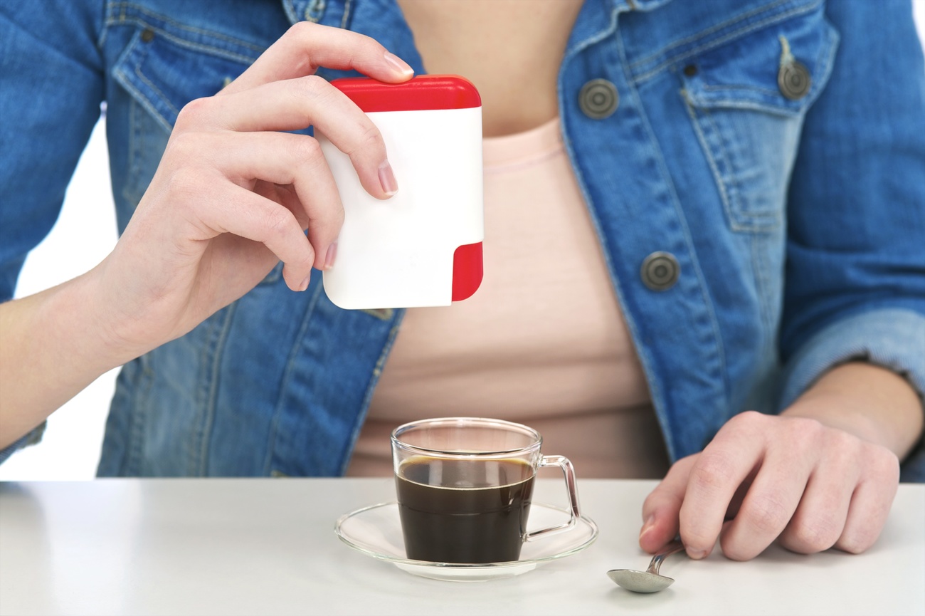Eine Frau gibt künstlichen Süsstoff in einen Kaffee