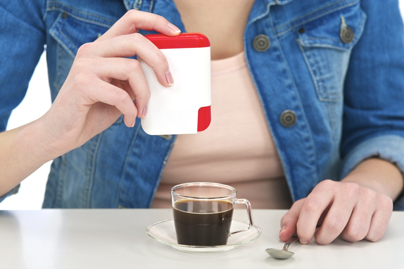 Una chica poniendo edulcorante en el café