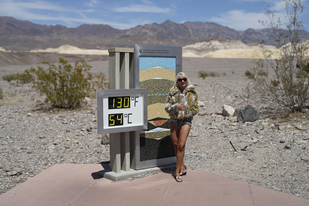 Una donna accanto a un termometro nel deserto
