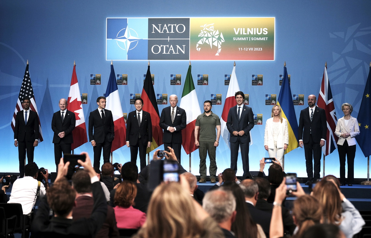 Президенты и премьер-министры стоят на сцене перед государственными флагами своих стран.