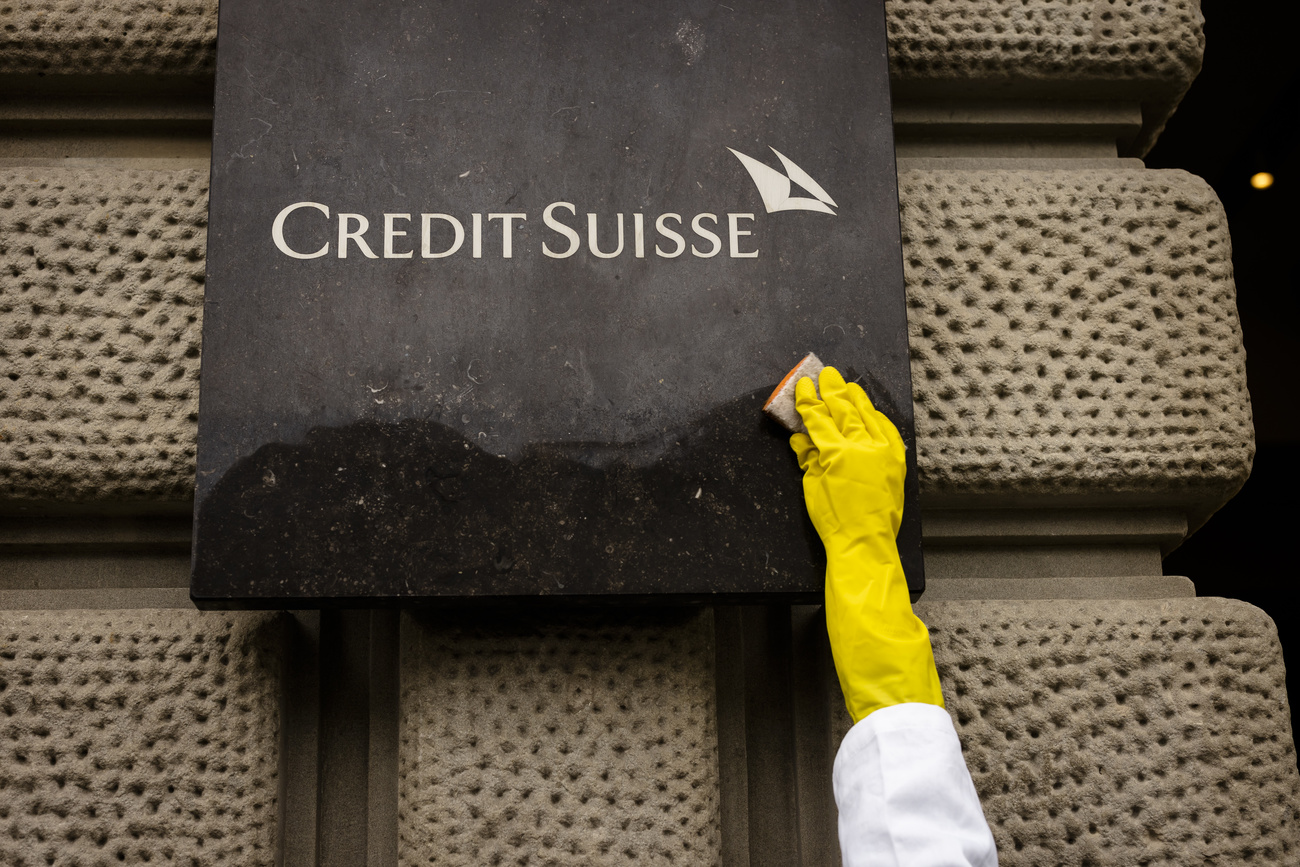 Persona limpiando un cartel de Credit Suisse