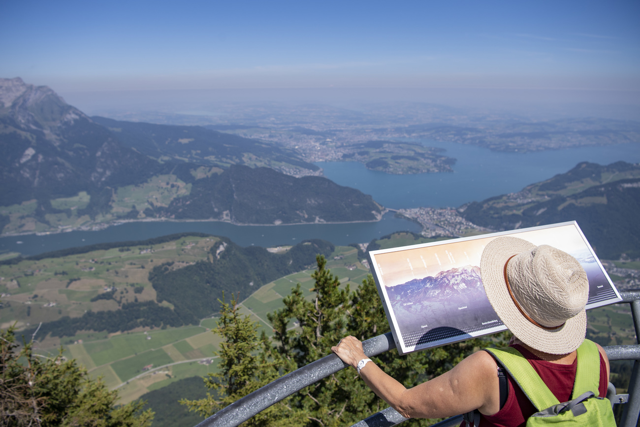 Eine Touristin blickt in den Schweizer Bergen von einer Terrasse auf das Bergpanorama.