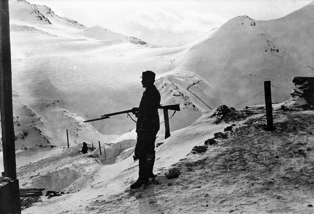 uomo con un fucile su una montagna innevata in una foto in bianco e nero