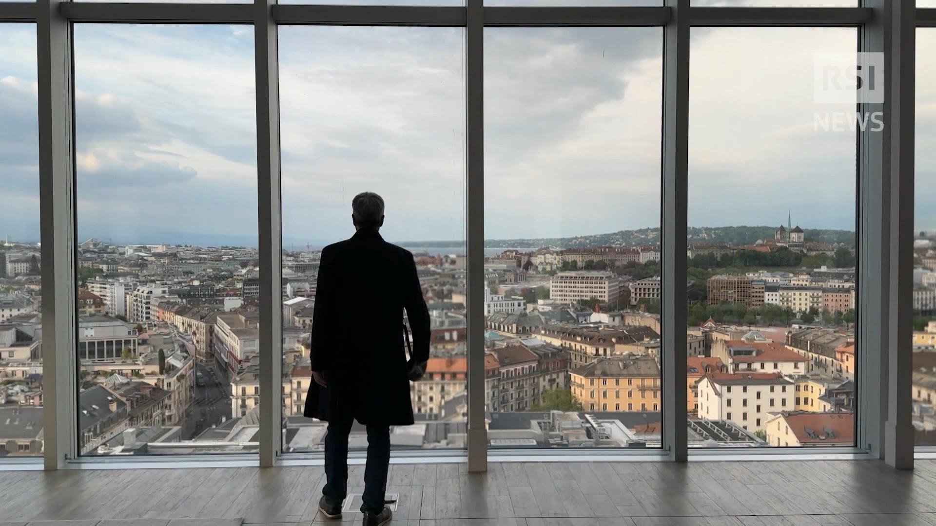 Ein Mann im Anzug steht in einem schicken Büro und blickt aus dem Fenster.