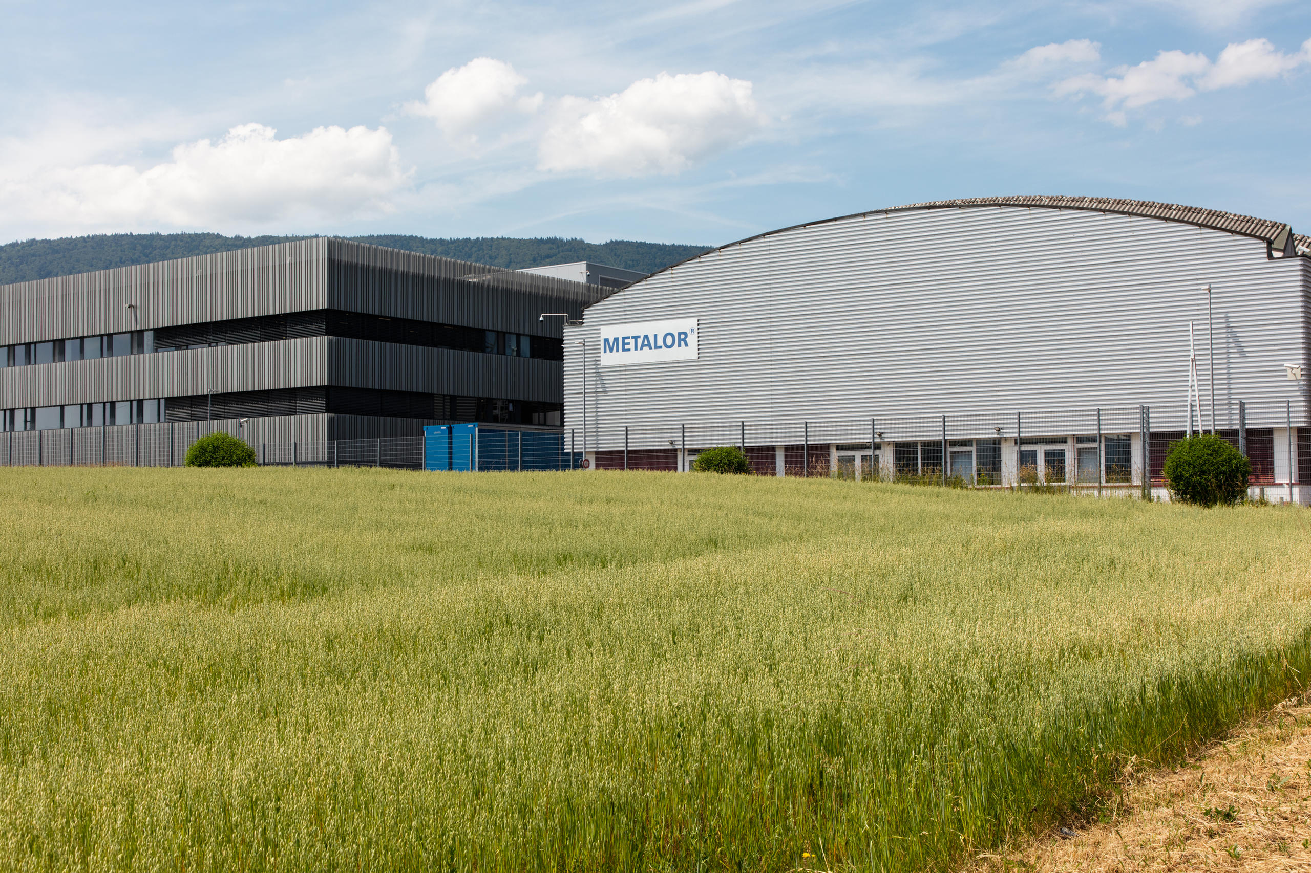Grauer Bürobau mit angrenzender Industriehalle in ländlicher Umgebung
