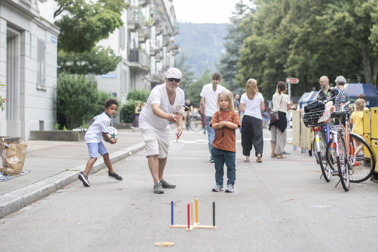 Ältere Menschen und Kinder spielen auf einer Strasse in der Schweiz