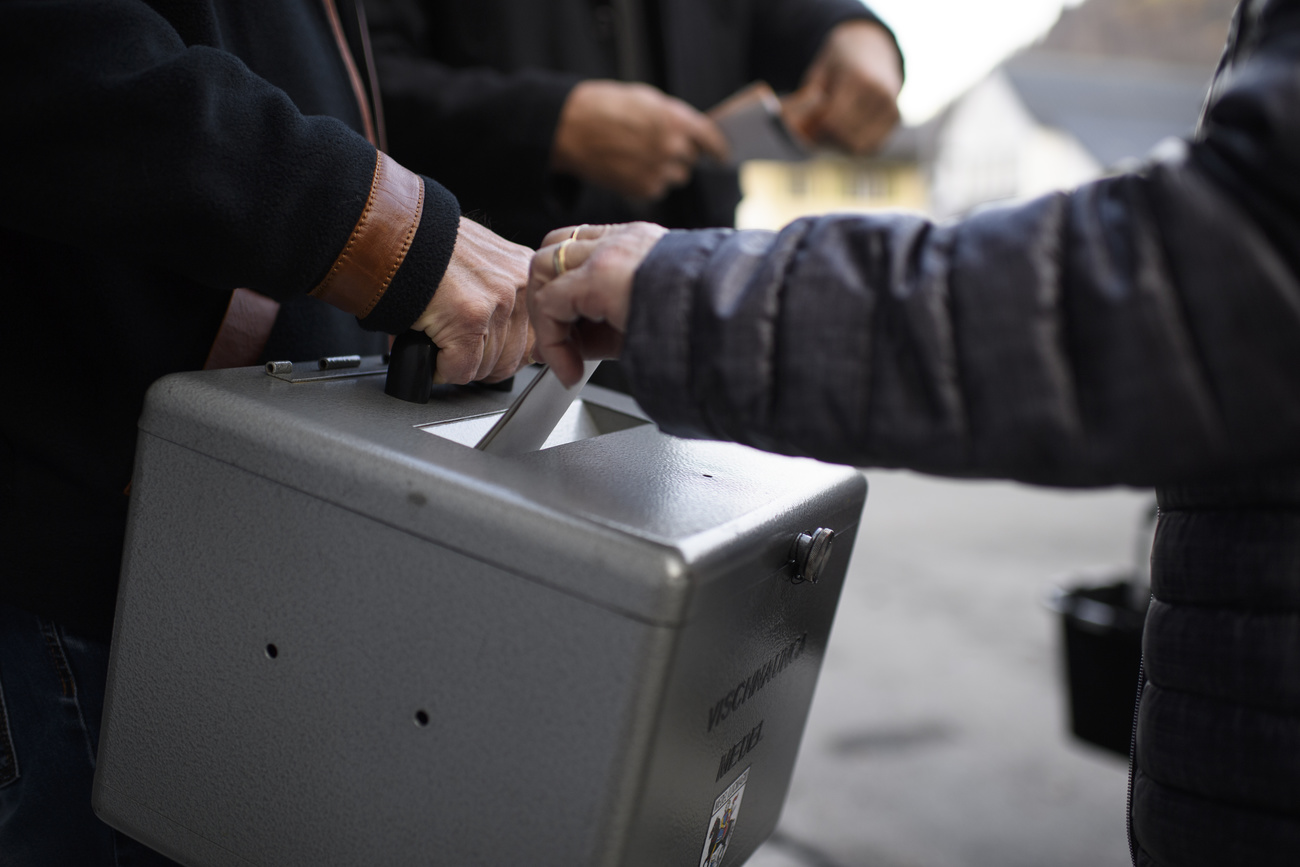 As pessoas colocam seus votos em uma urna.