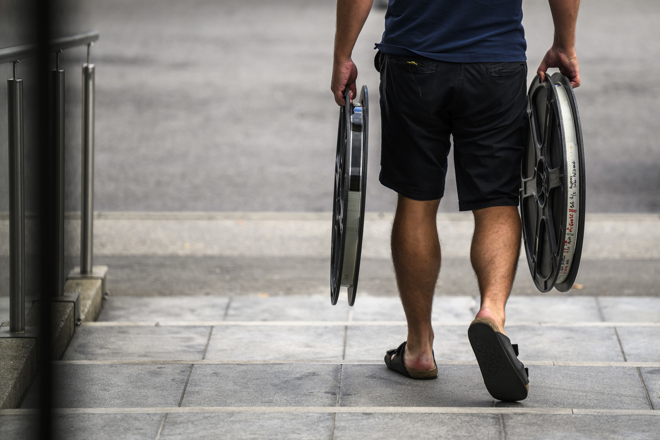 bottom half of somebody carrying two large film reels