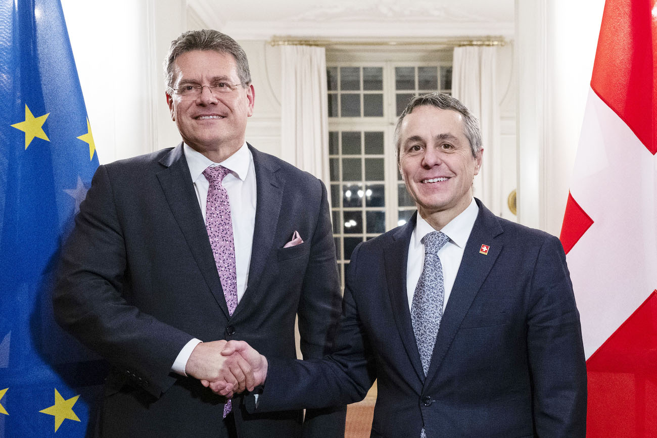 Sefcovic und Cassis reichen sich die Hand und schauen in die Kamera