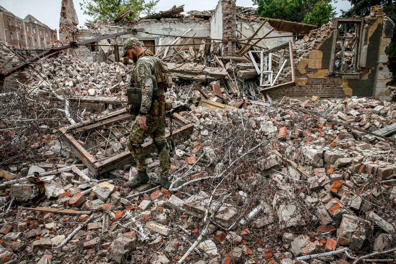Un soldado ucraniano camina entre los escombros causados por la explosión de un cohete ruso.