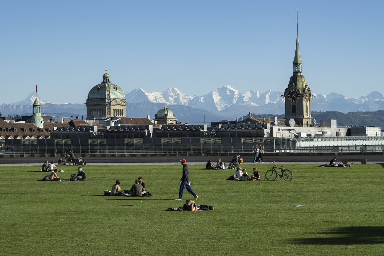 Des personnes prennent le soleil sur la pelouse non loin du Palais fédéral à Berne