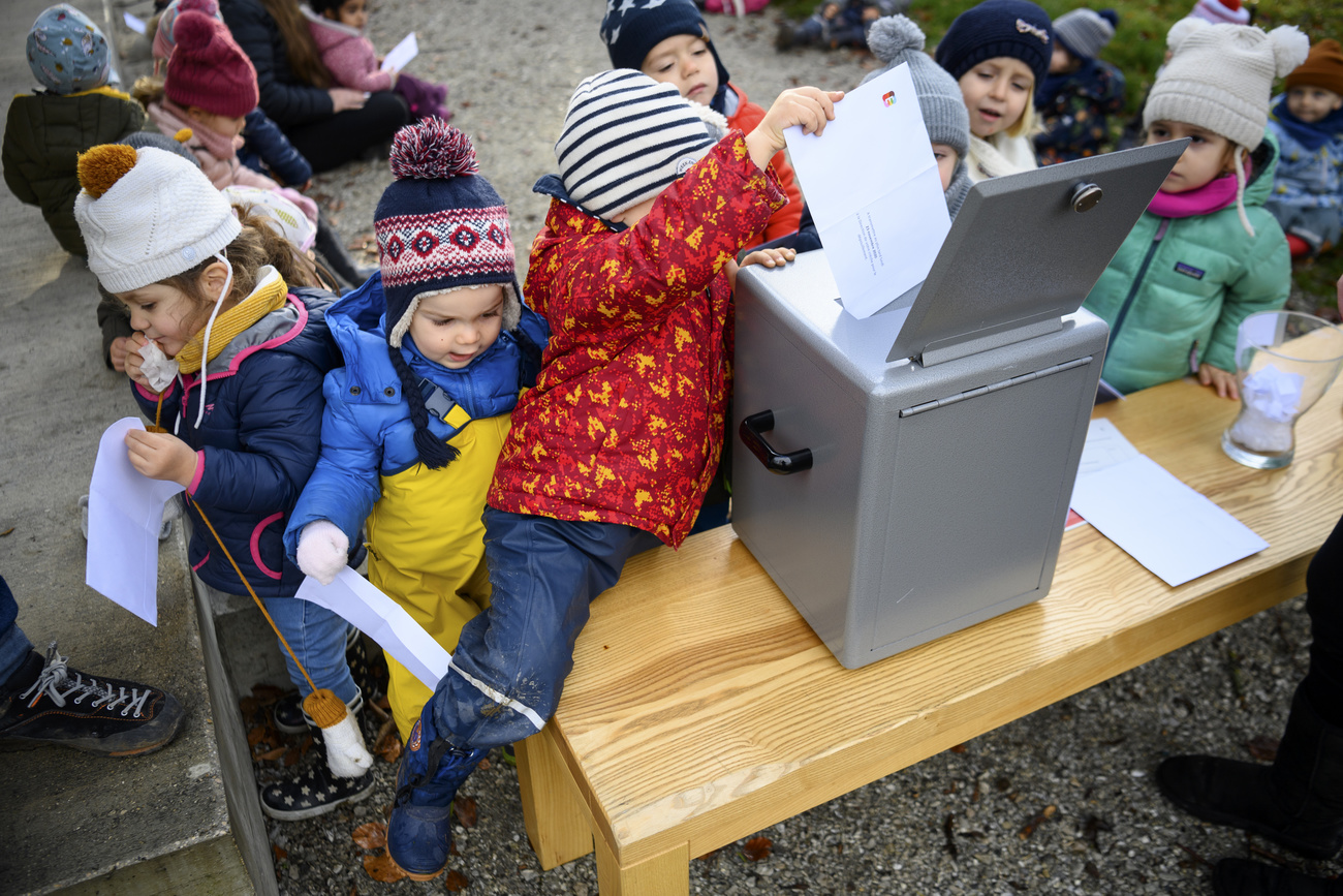 children putting papers into ballot box