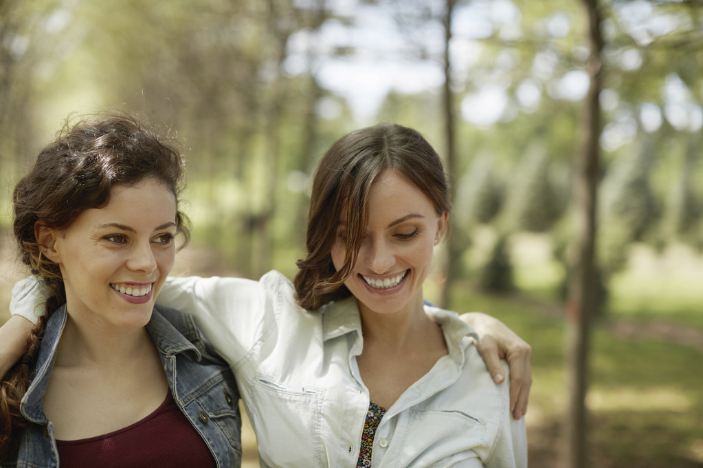 Zwei junge Frauen, die miteinander befreundet sind und lächeln