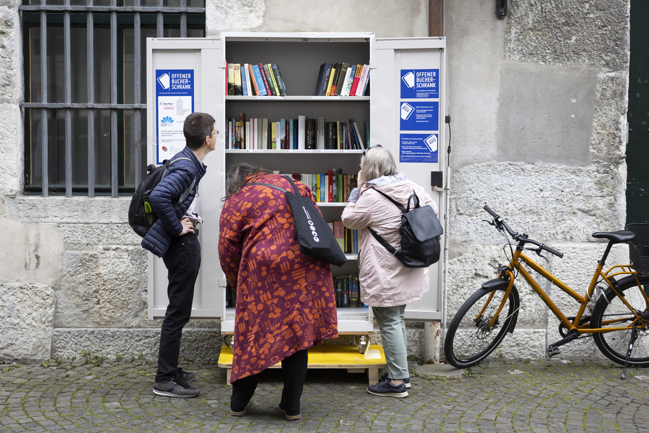 Personen stehen vor einem offenen Bücherschrank, der das tauschen von Büchern ermöglicht