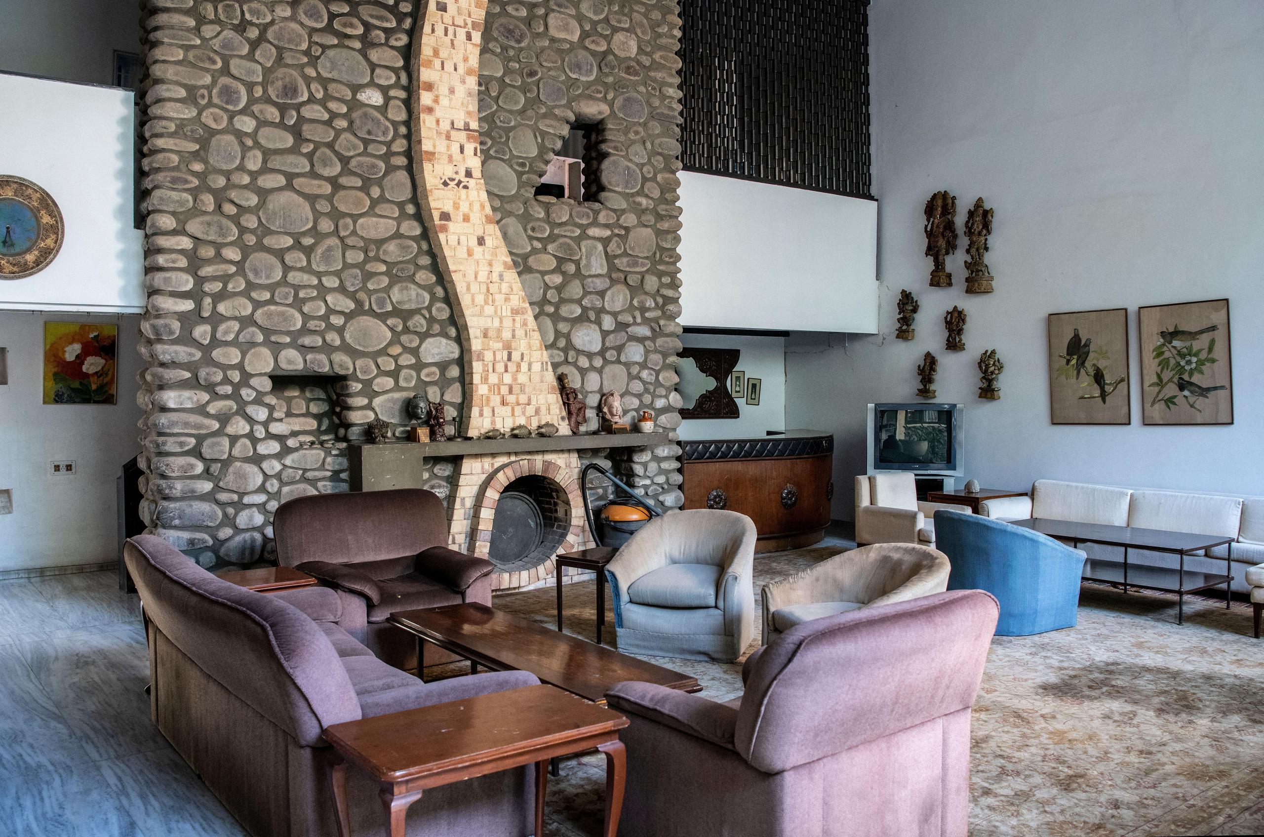 Sofa, Tisch und Stühle vor einem steinernen Kamin in einem Architektenhaus