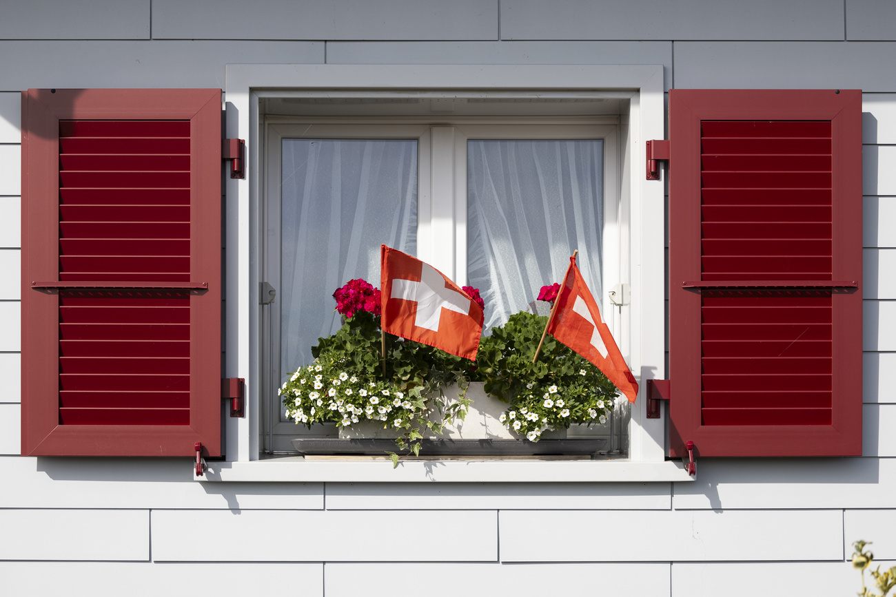 Photo of a window with flowers and two Swiss flags