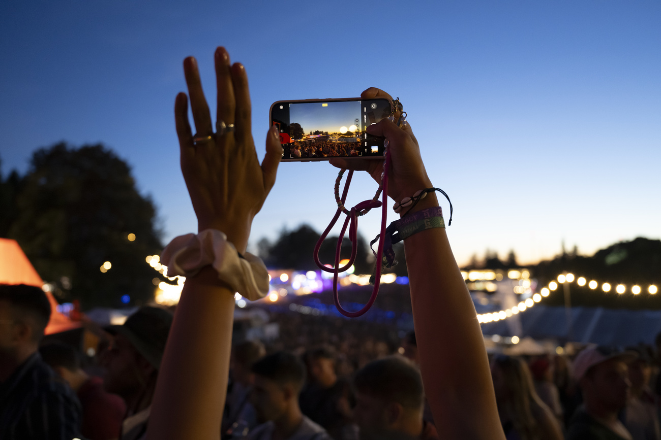 Una giovane donna filma con il telefonino un concerto durante il Fetival del Gurten a Berna.