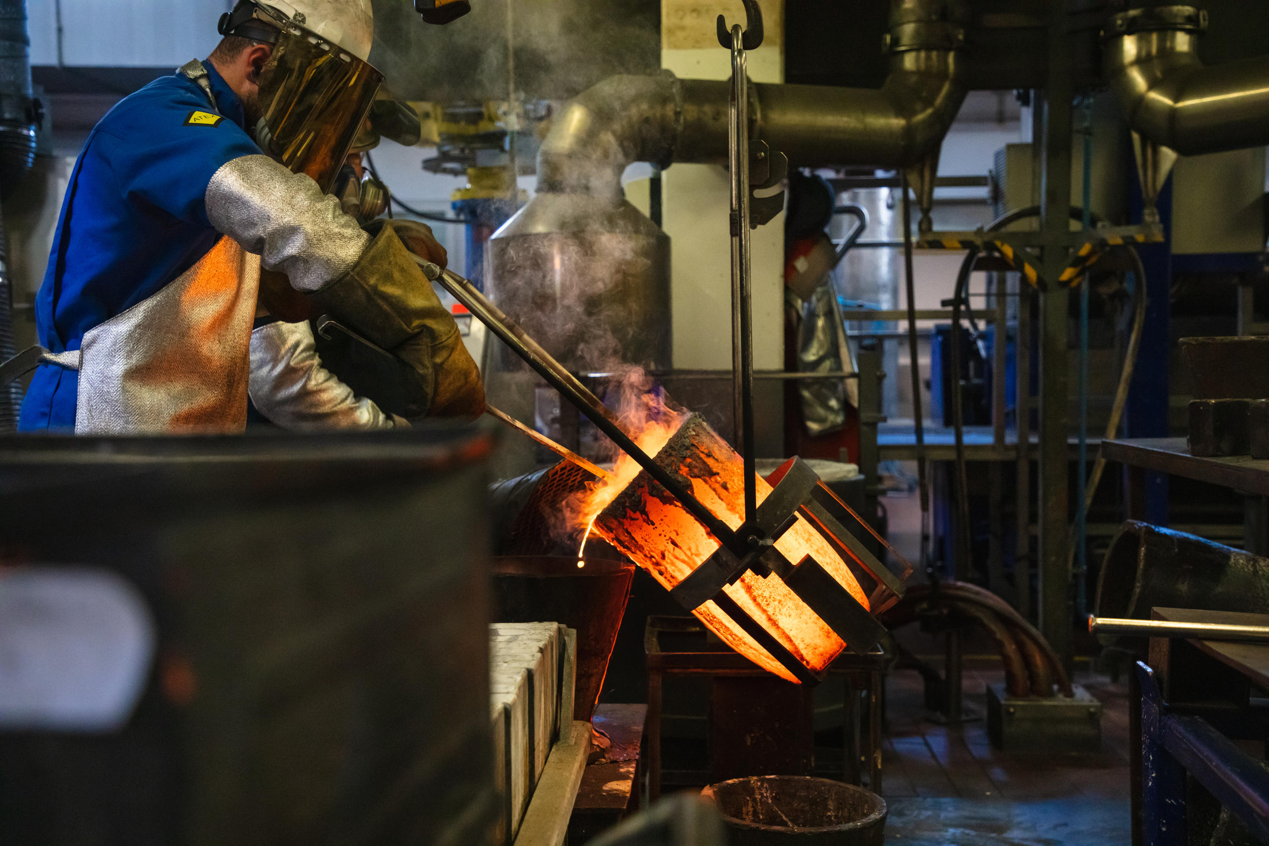 Man pours molten metal into rectangular moulds