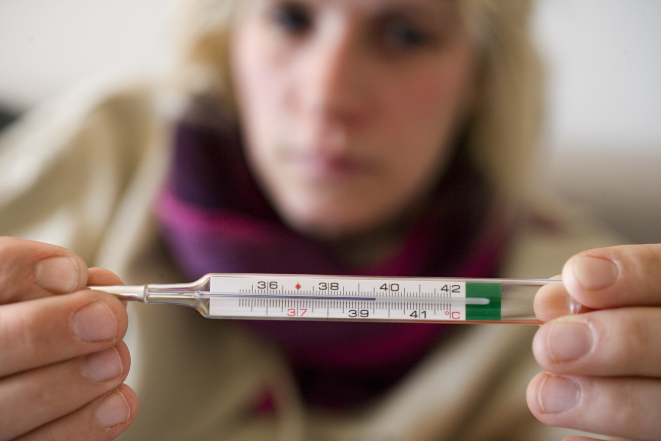 woman holding a thermometer showing high temperature