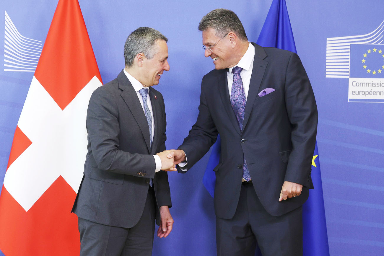 Ignazio Cassis dándole la mano a Maros Sefcovic delante de la bandera suiza y la de la UE