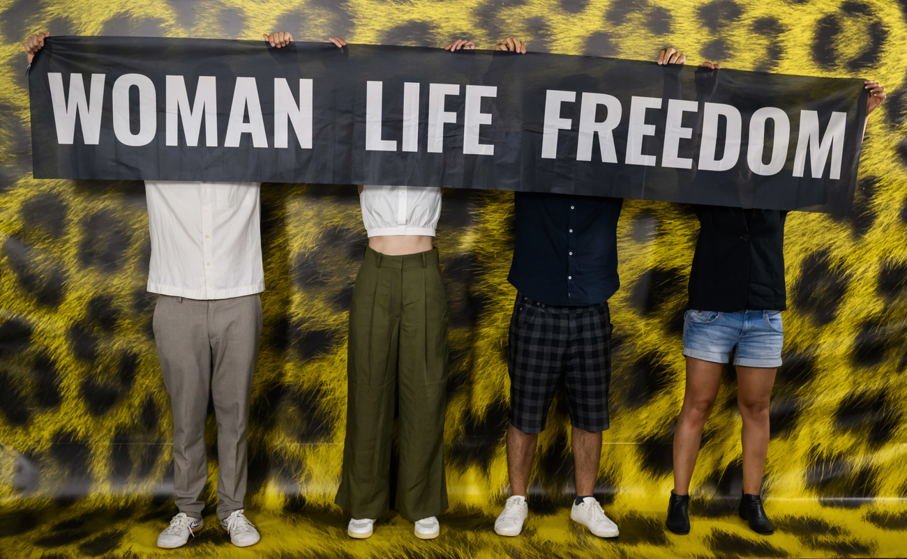 Cuatro personas en el photocall del Festival con una pancarta que pone Woman Life Freedom
