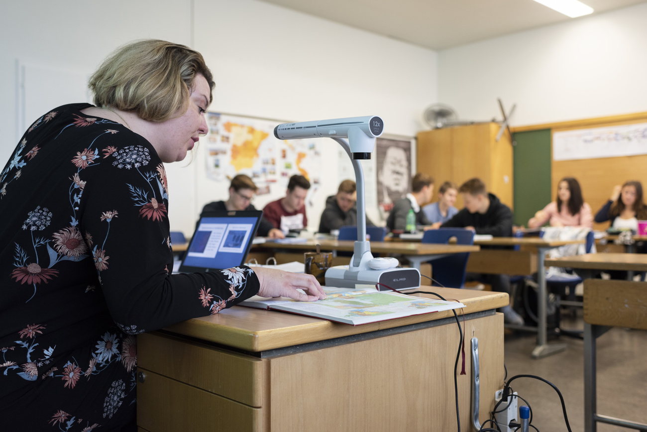 Imagem de uma sala de aula com professores usando um laptop