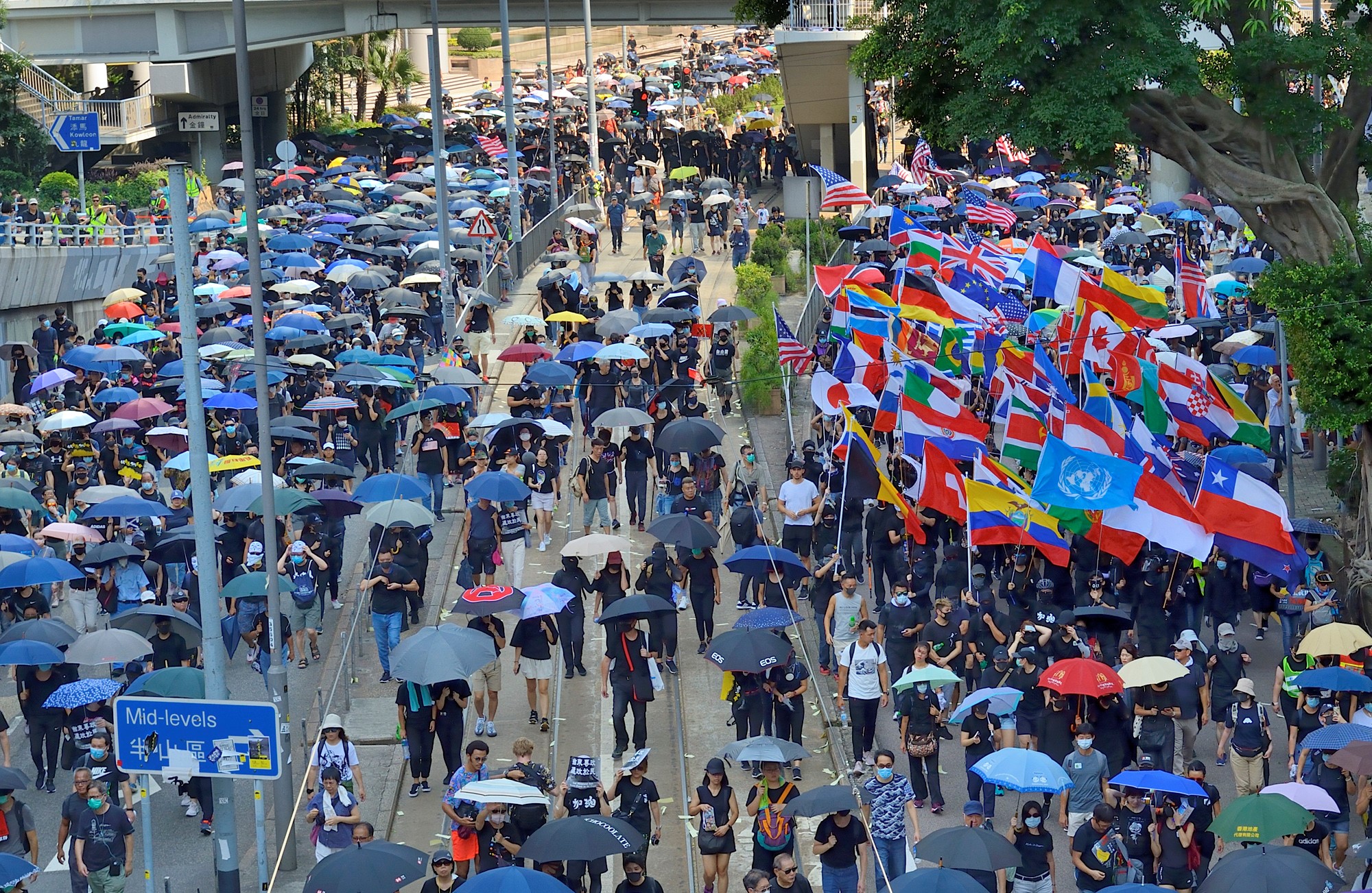 傘をさしてデモ行進する人々