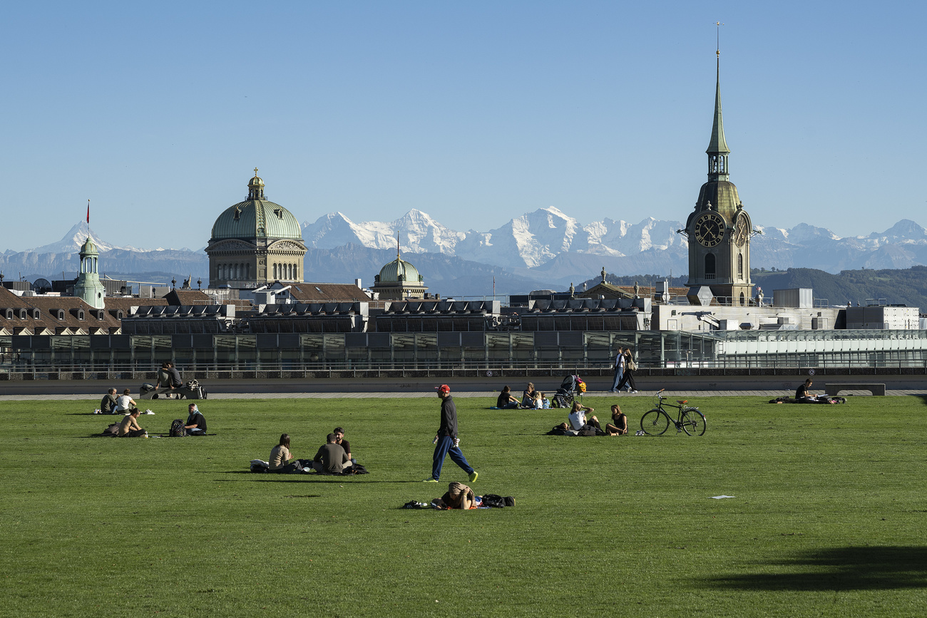 Blick von der grossen Schanze in Bern auf Bundeshaus und eine Kirche und die Alpen im Hintergrund