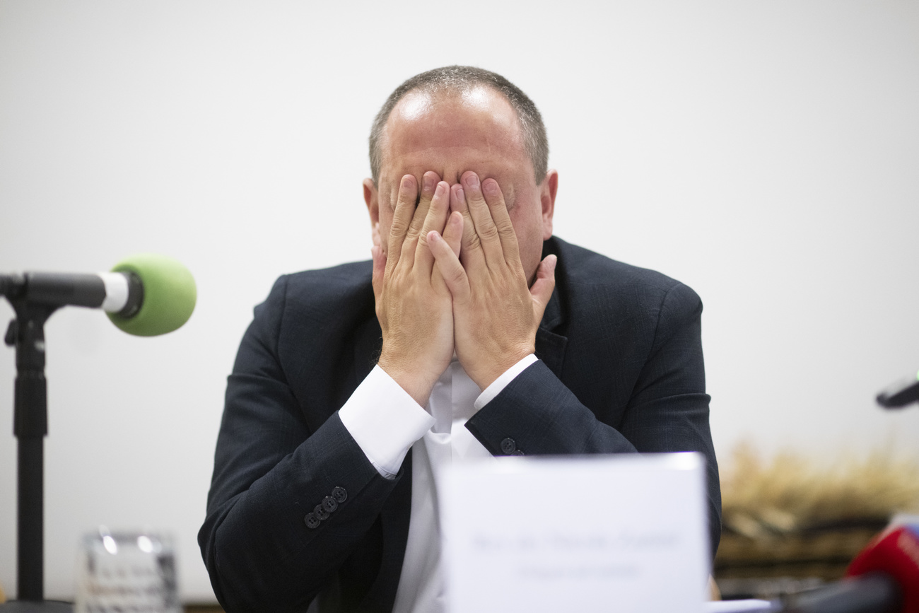 Catholic cleric holds hands over face.