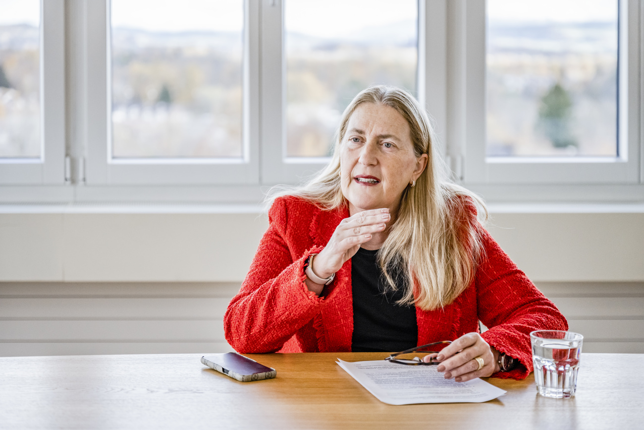 Frau in rotem Blazer sitzt an einem tisch in einem weissen Büro
