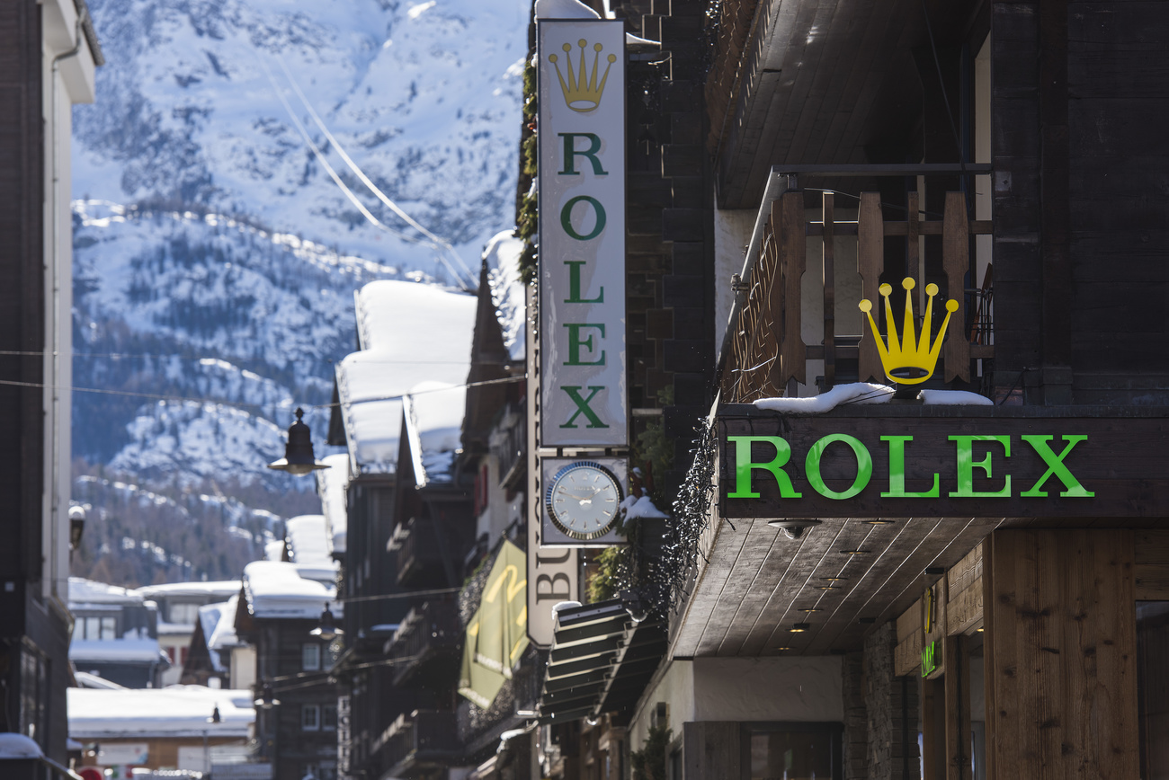 Rolex-Schild an einem Haus, mit Alpen im Hintergrund