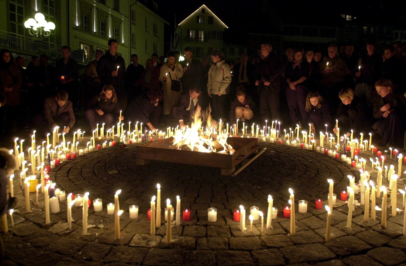 Ein Kreis aus Kerzen, darum Menschen im Dunkeln
